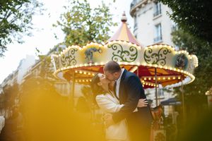 Mariés s’embrassant devant un manège illuminé, scène festive et romantique.