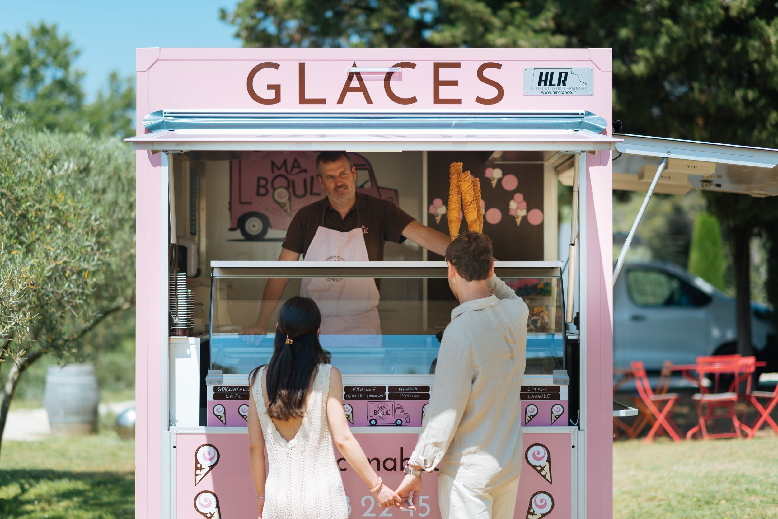 Couple en tenue de mariage commandant une glace à un stand vintage, scène légère et estivale.
