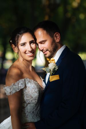 Portrait rapproché d’un couple de mariés souriant, lumière douce et regard complice.