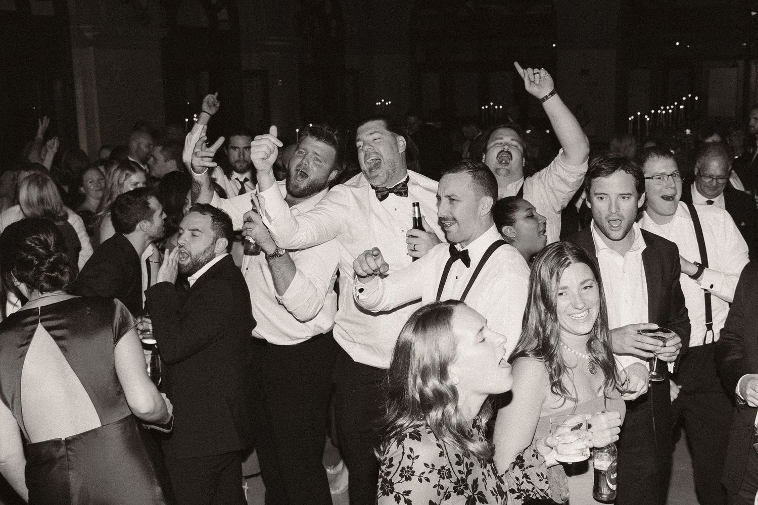 Crowd surfing at a concert with raised hands and a chandelier visible in the background.