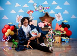 Toy Story themed toys arranged against a blue backdrop with white cartoon clouds.