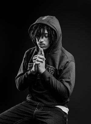 A moody series of black and white portraits showing a person in a dark hoodie against a black background.