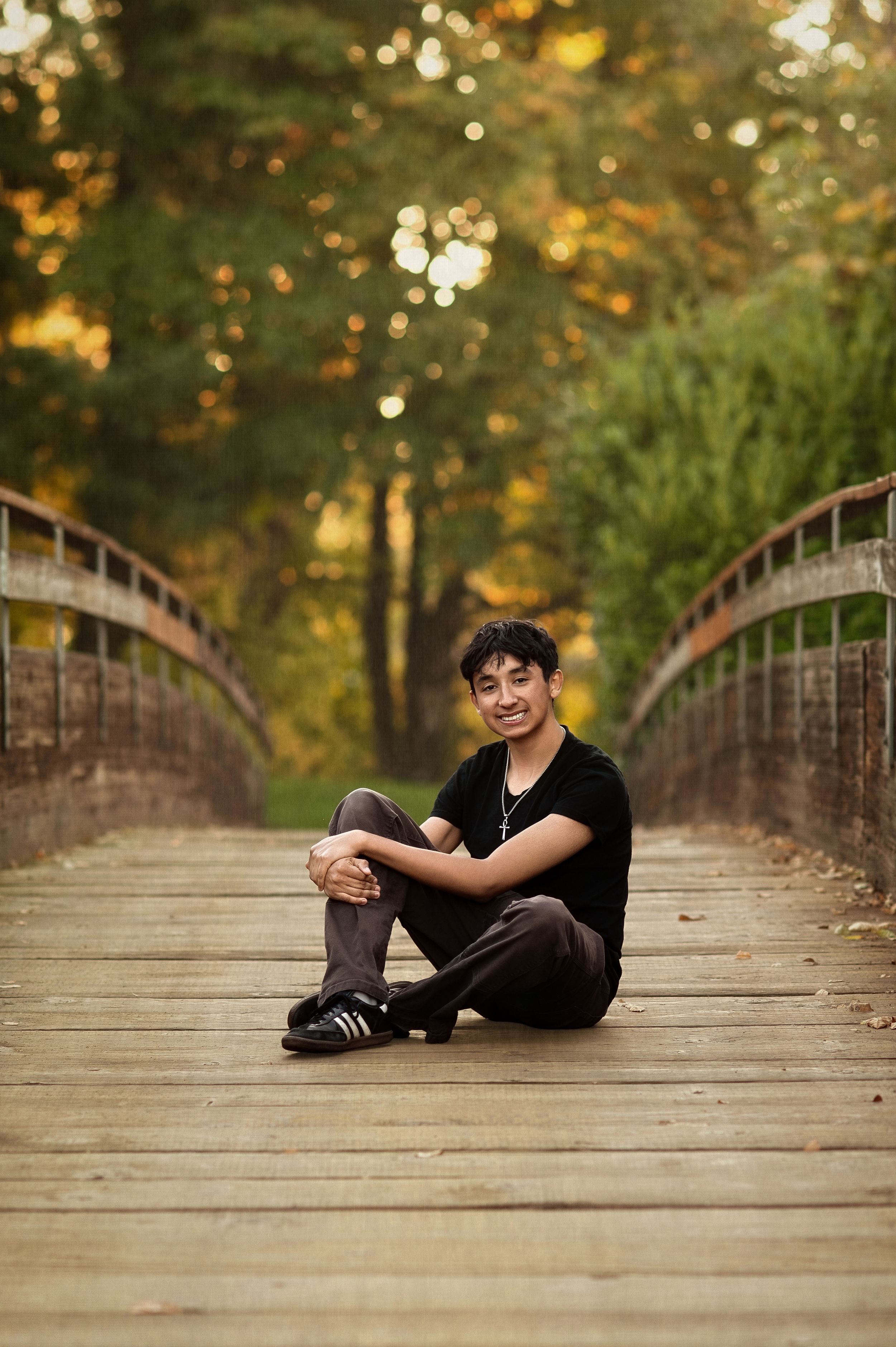 A series of photos showing someone relaxing on a wooden bridge surrounded by autumn trees in a park setting.