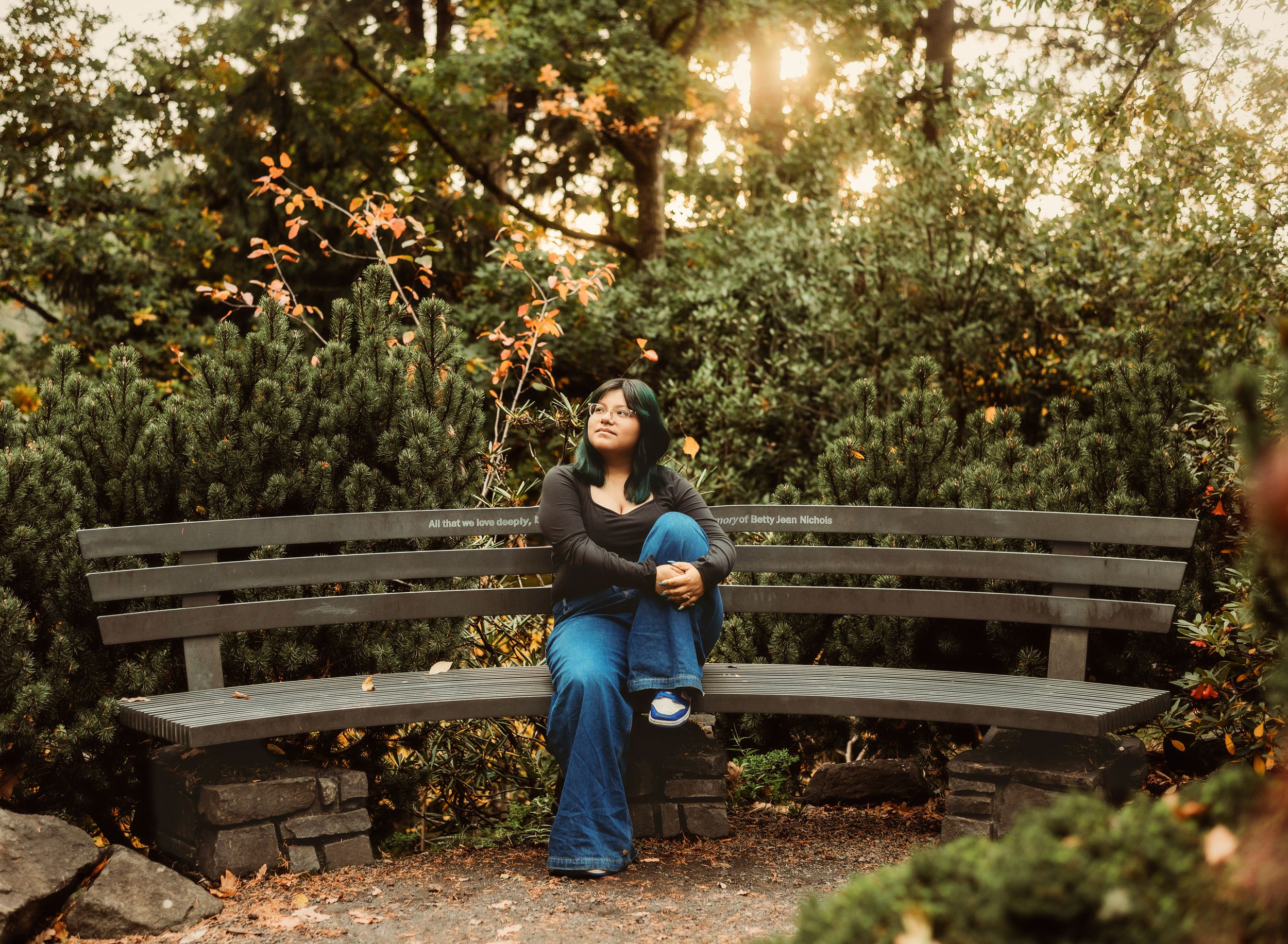 A person in a blue dress twirls gracefully through a lush garden setting during golden hour.