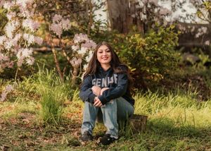 Person sitting outdoors in autumn scenery with fallen leaves and natural lighting.