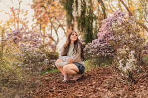 Someone relaxing on ground surrounded by autumn foliage and dappled sunlight in park setting.