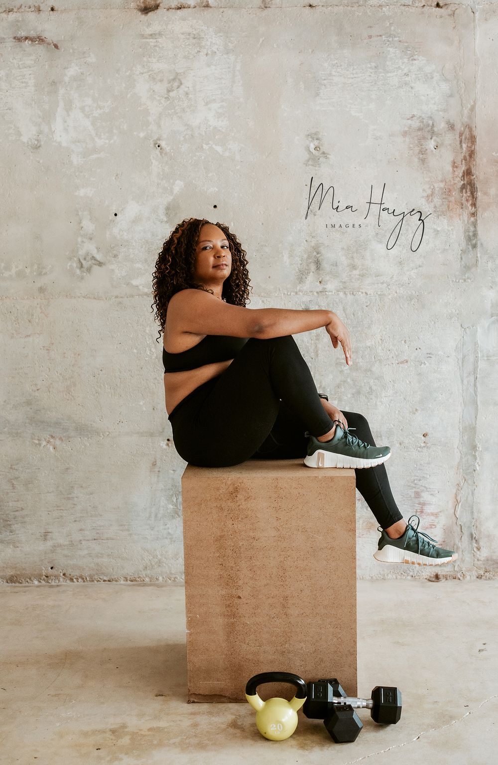 Artistic portrait series featuring person in black outfit sitting on brown cube against textured wall.