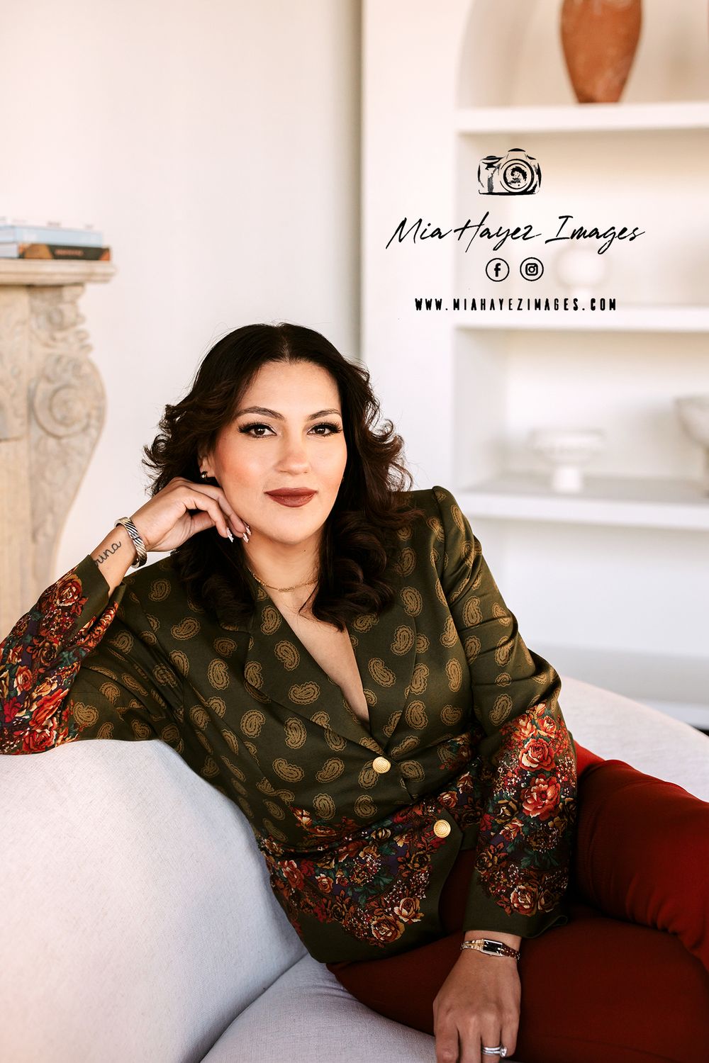 Professional portrait session featuring elegant polka dot blouse and burgundy styling on white couch.
