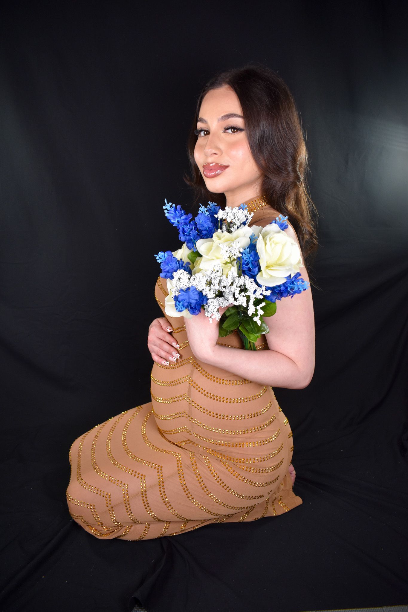 pregnant model kneeling holding blue flower bouquet