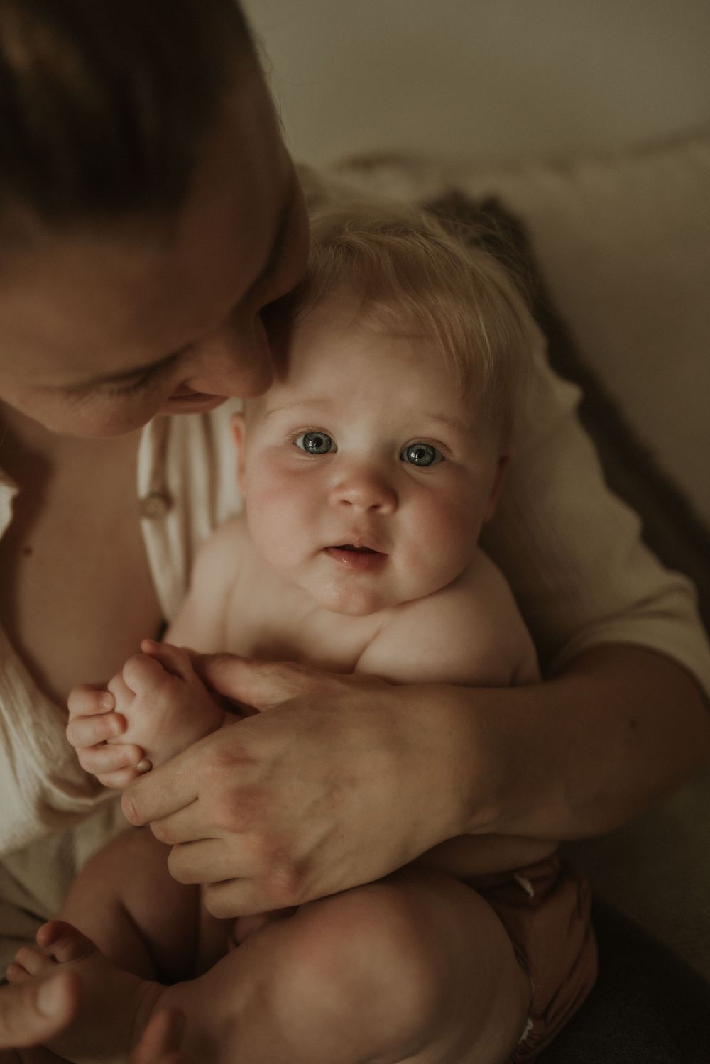 Tender moment between parent and infant in warm, intimate lighting.
