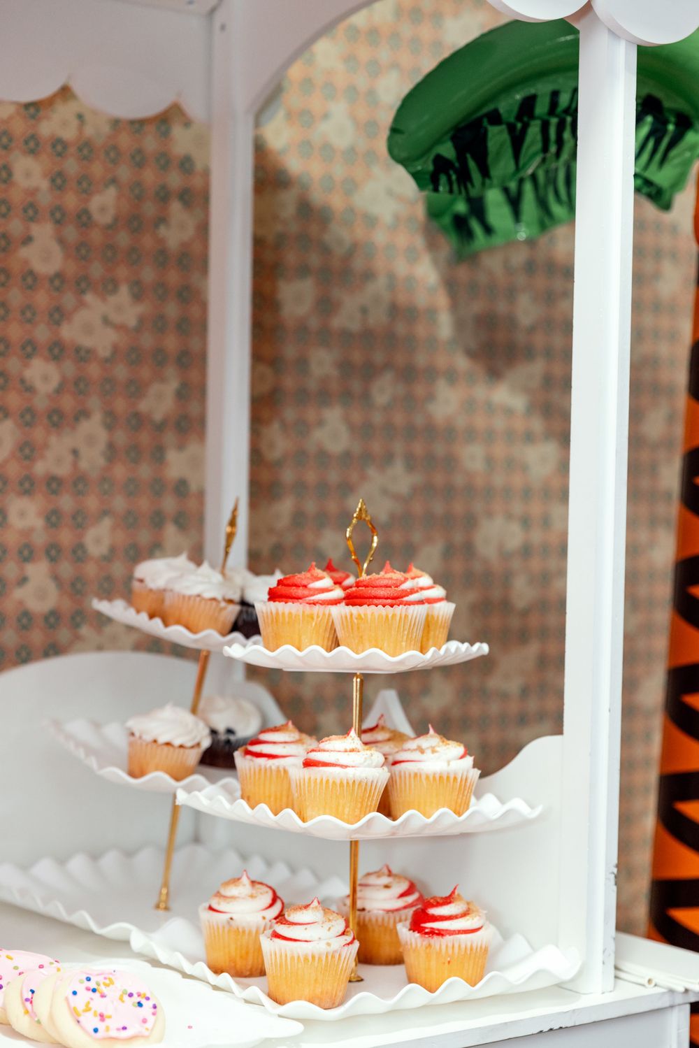 A tiered display stand of cupcakes with red and white frosting decorations.