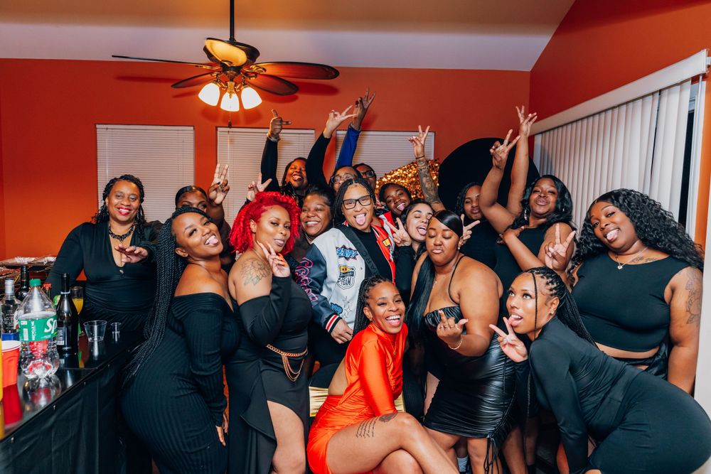 Group of friends posing together at a lively party with red walls.