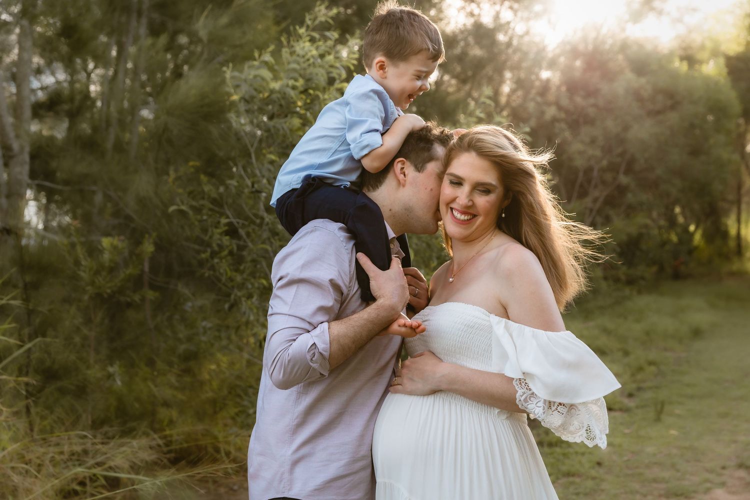 Couple walking arm in arm as wife looks around to photographer during Brisbane maternity shoot