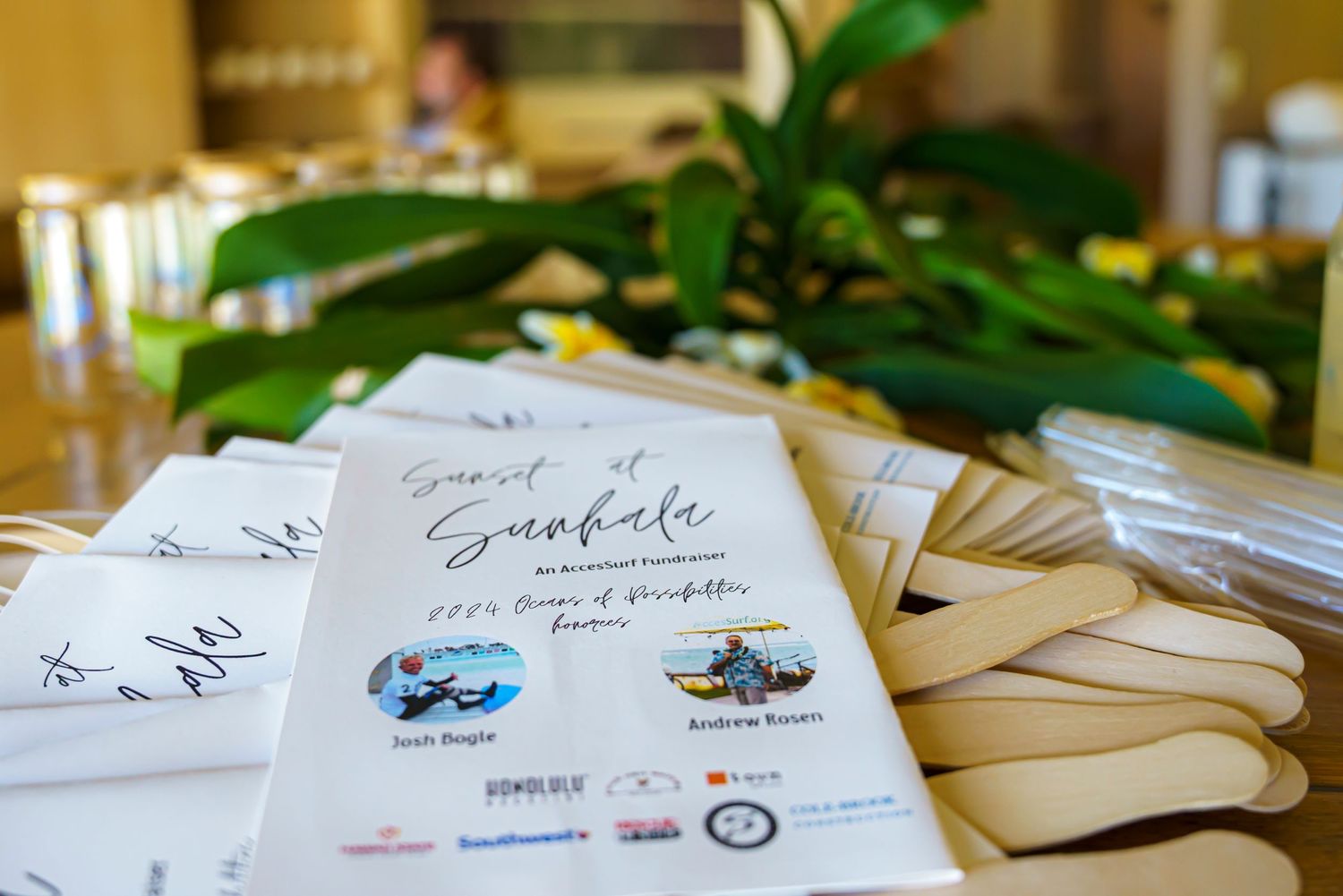 Custom event invitations and signage displayed on a wooden table at a tropical destination event.