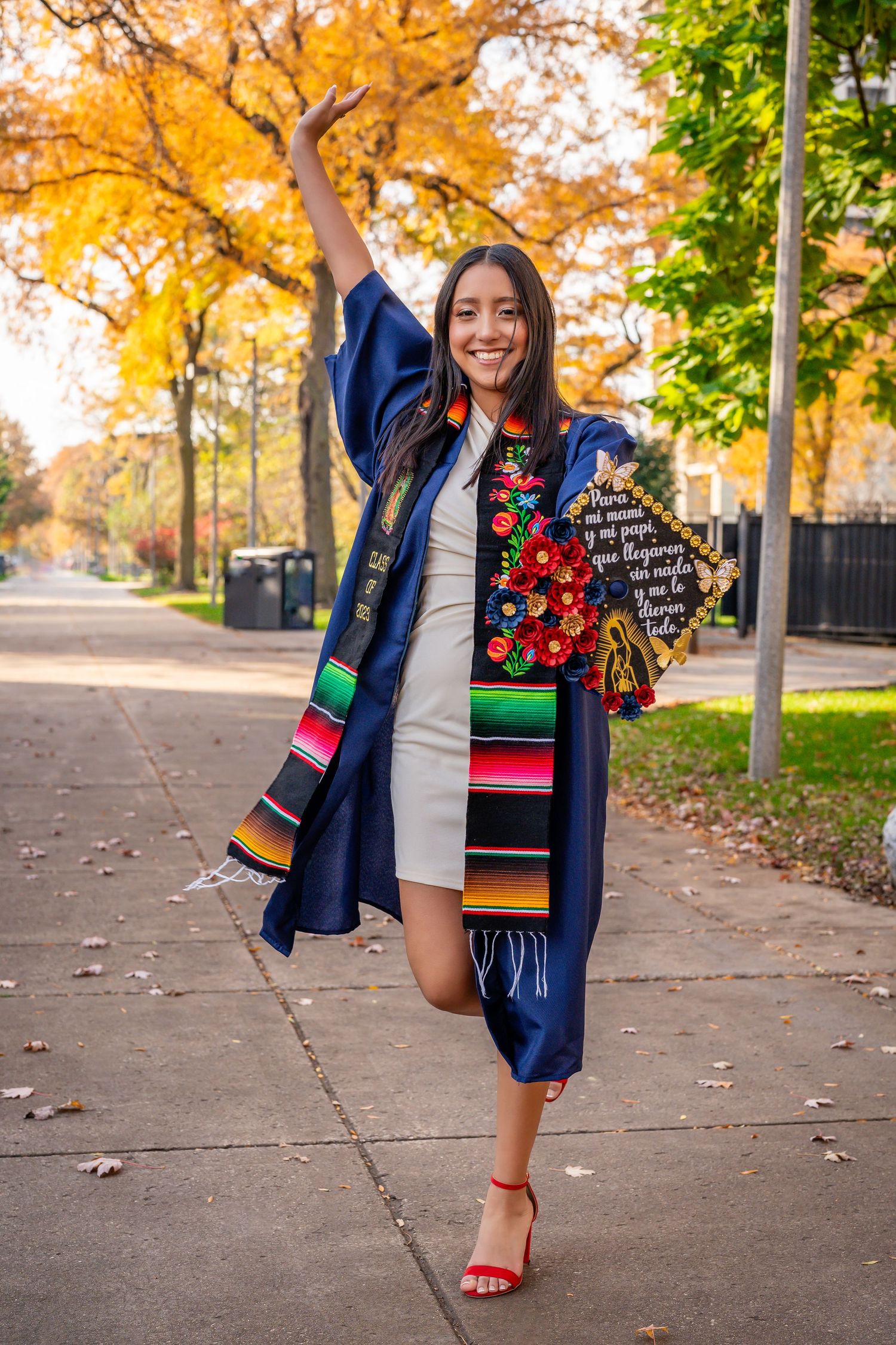 Graduation photos showing colorful Mexican serape stole and red heels on autumn campus path.