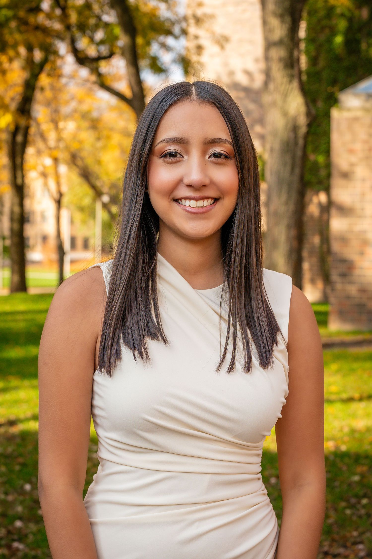 Portrait series in white sleeveless top against autumn foliage background.