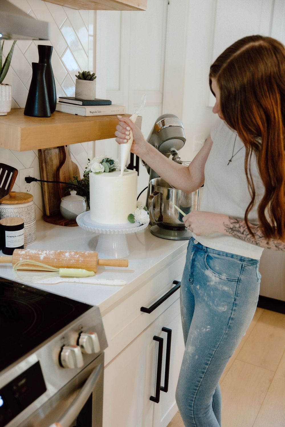 Person baking in a minimalist white kitchen with professional equipment.