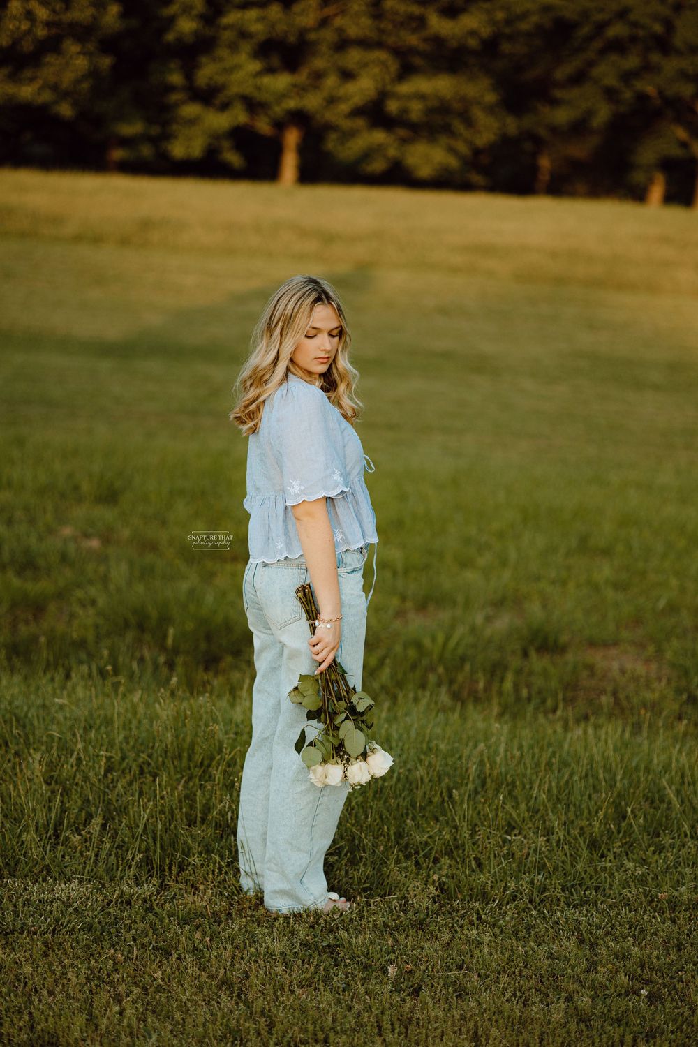 A dreamy outdoor portrait session in a grassy field at golden hour.
