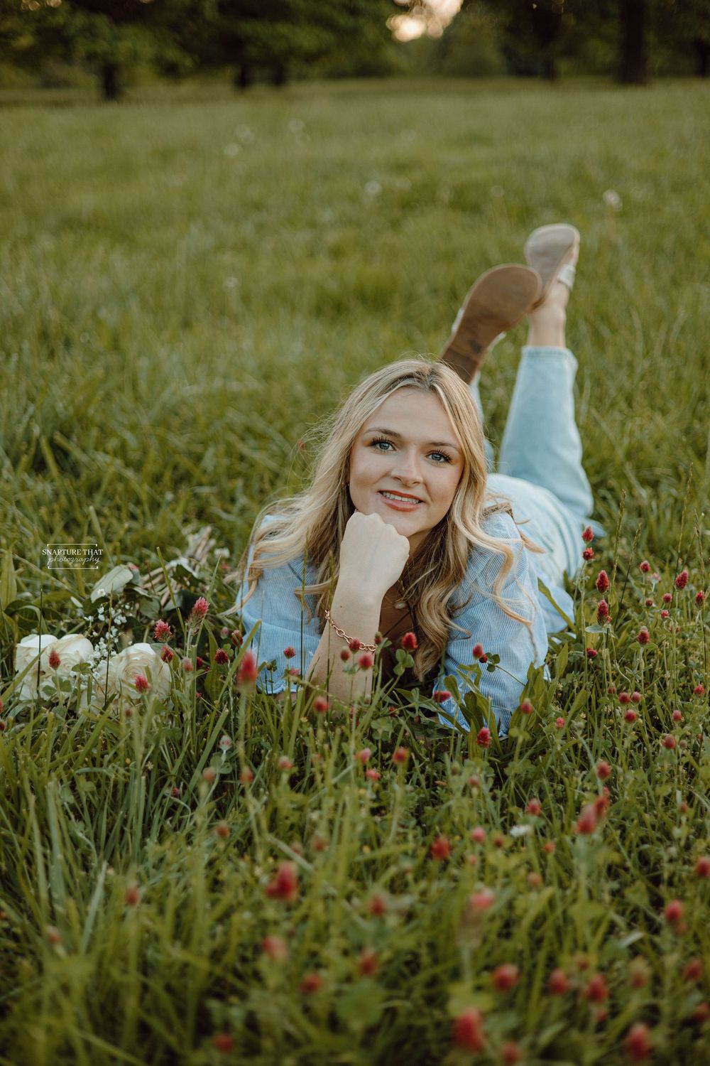 Romantic portrait in a wildflower meadow with red flowers and green grass.