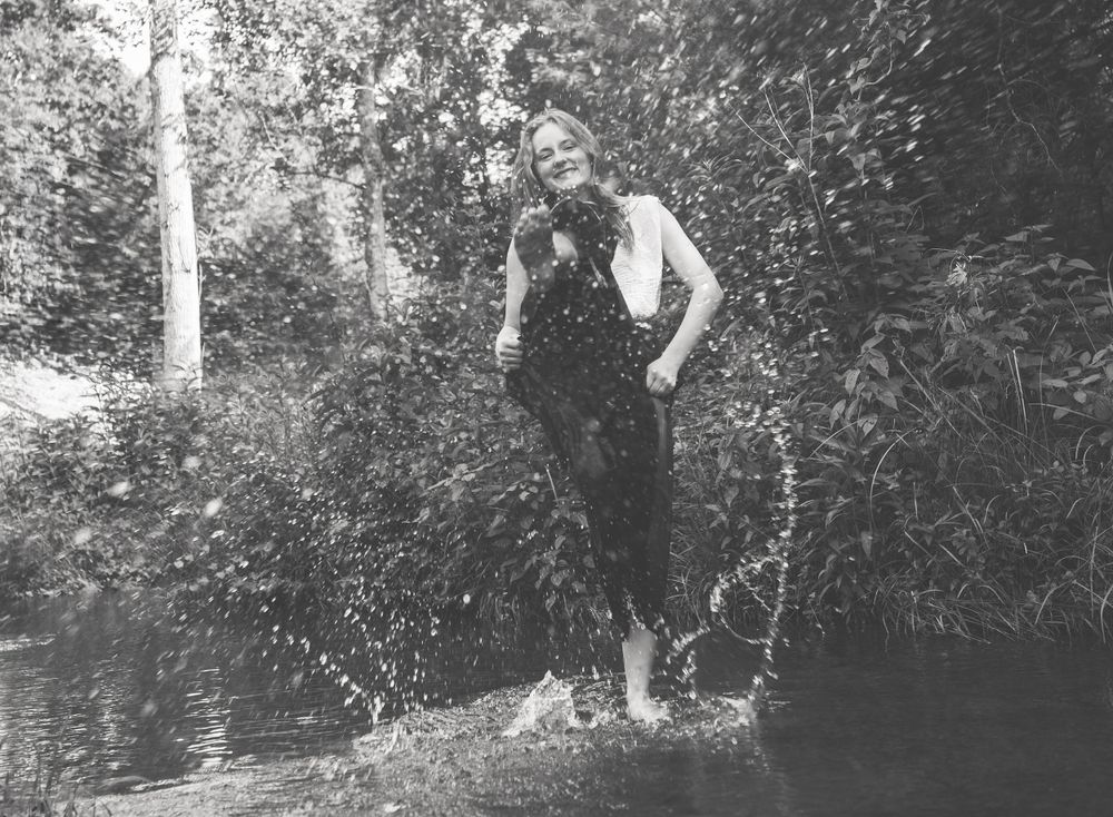 Black and white senior portrait session splashing in the creek for this senior girl in Cantonment, Fl