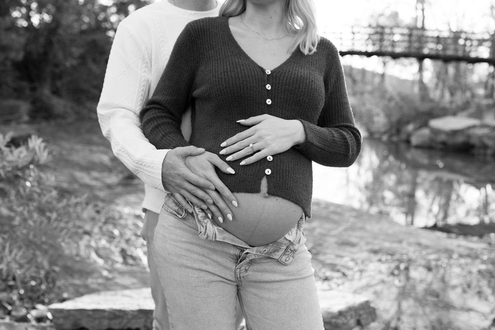 A series of black and white cropped photos showing hands resting on a pregnant belly in an outdoor setting.