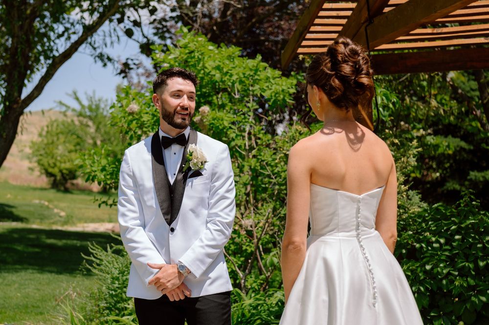 A couple in wedding attire shares a tender moment together in a lush garden setting.