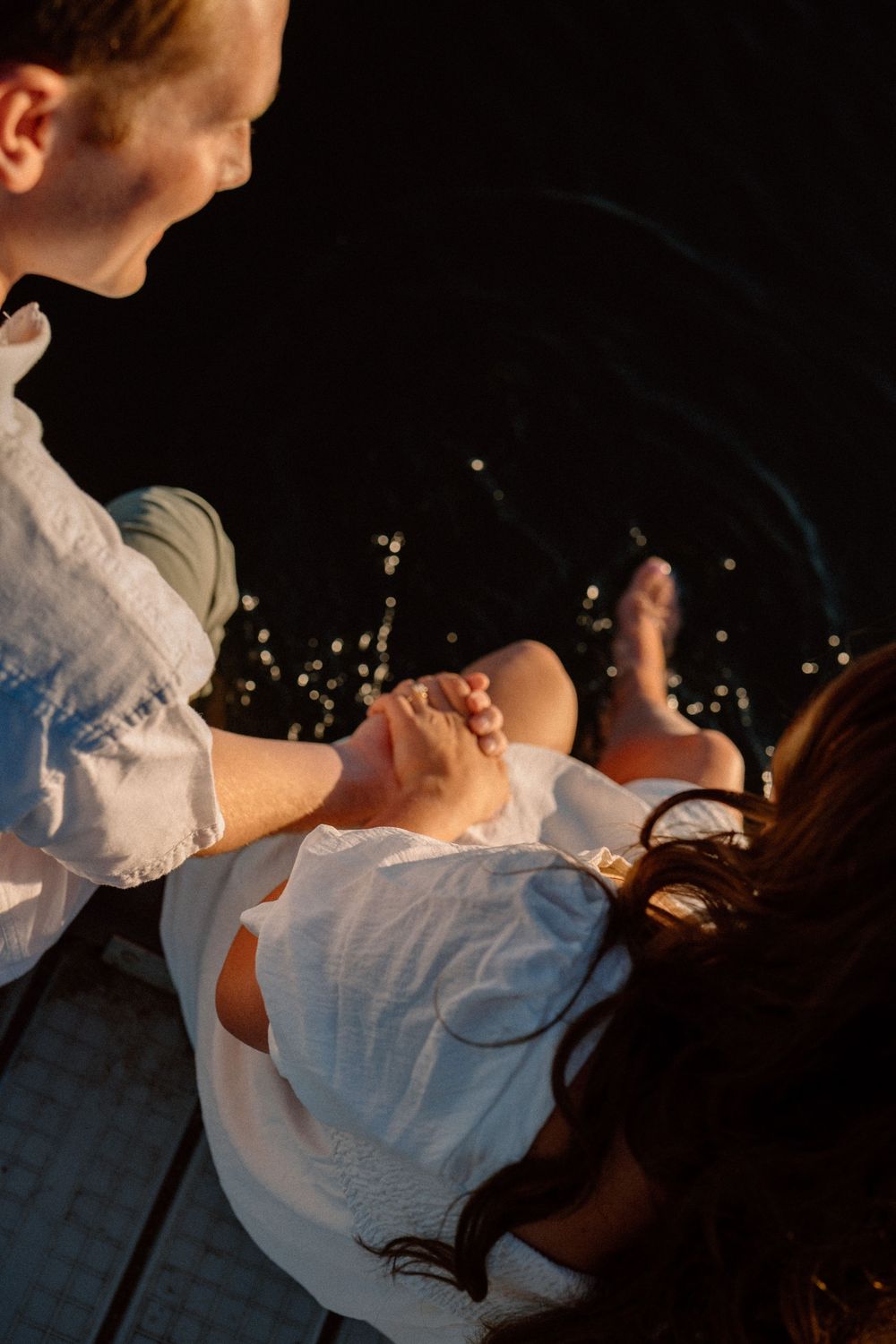 A couple dancing together at night with twinkling lights in the background creating a romantic atmosphere.