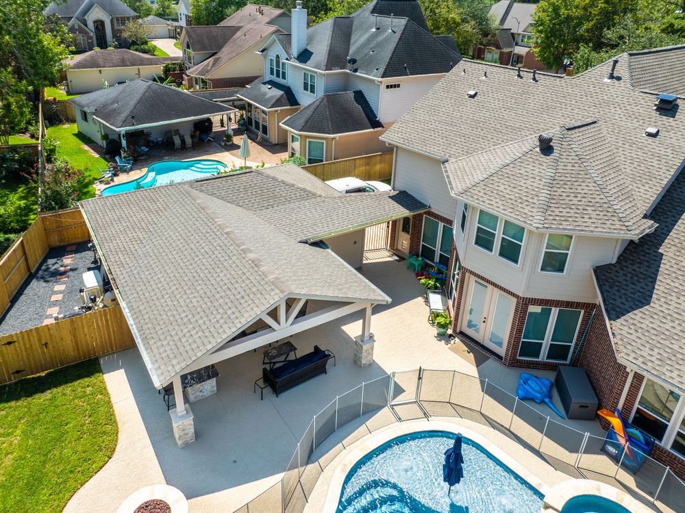 Aerial view of luxurious home with covered outdoor living area and curved swimming pool.