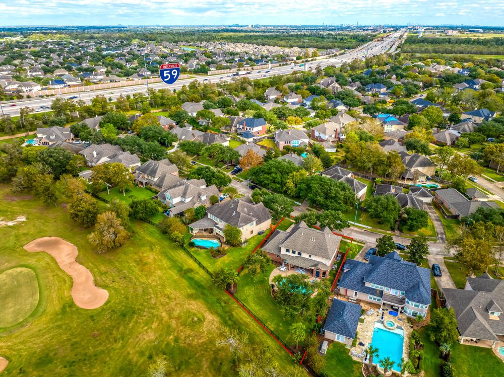 Aerial view of suburban neighborhood with golf course and swimming pools.