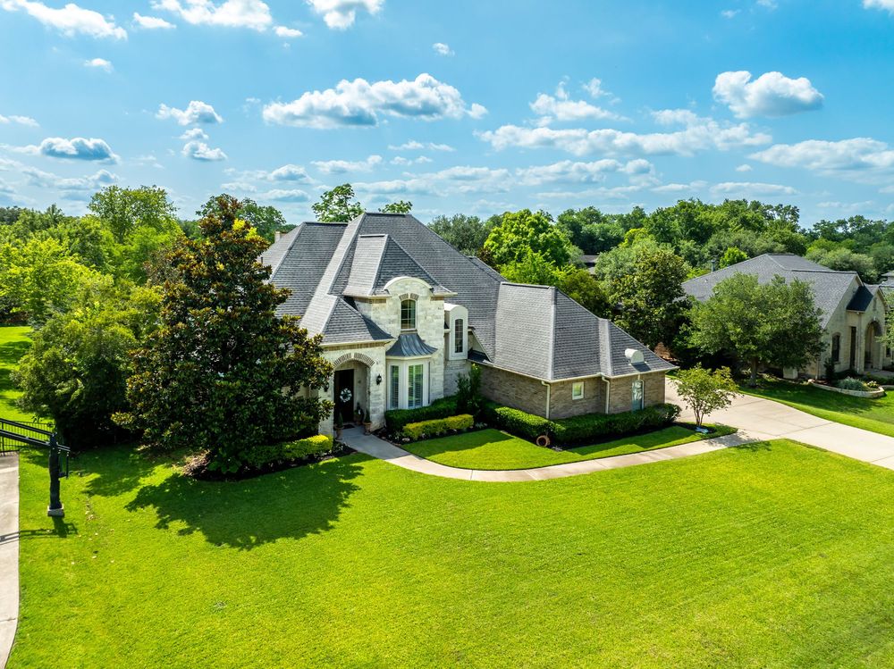 Aerial drone view of luxurious white houses with manicured lawns and driveways in an upscale suburban neighborhood.