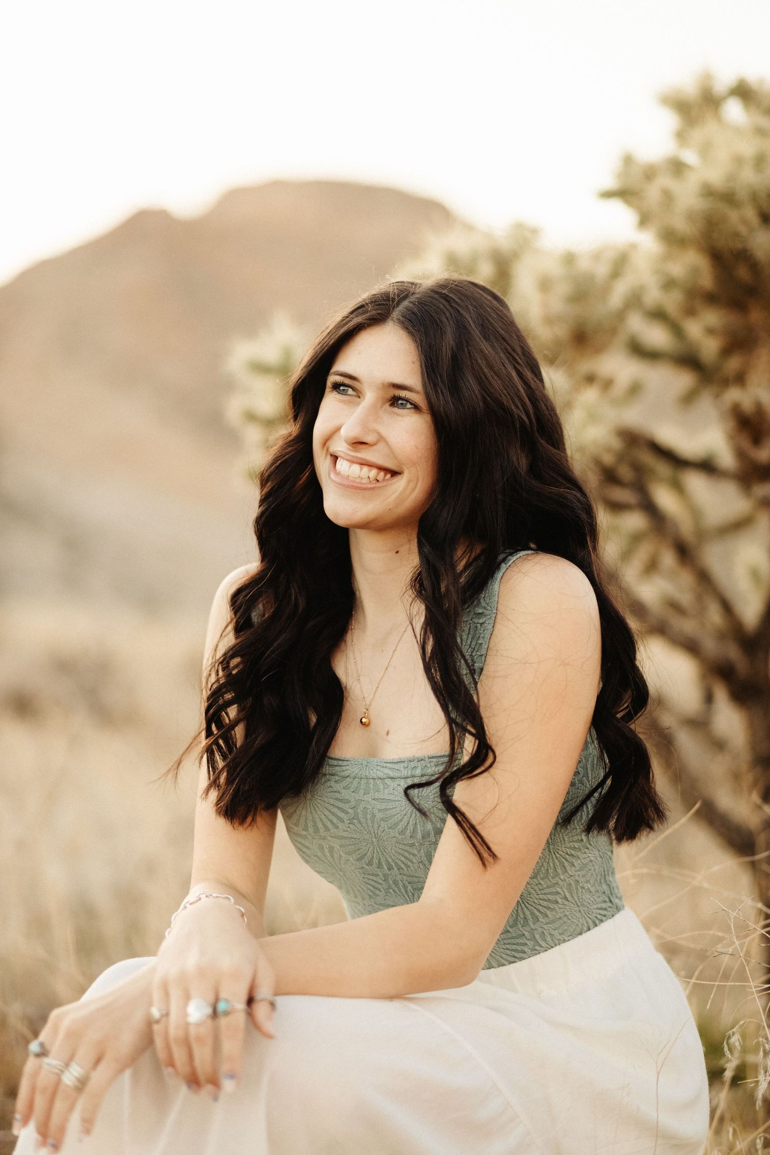 Joyful portrait series in sage green top against desert landscape at golden hour.