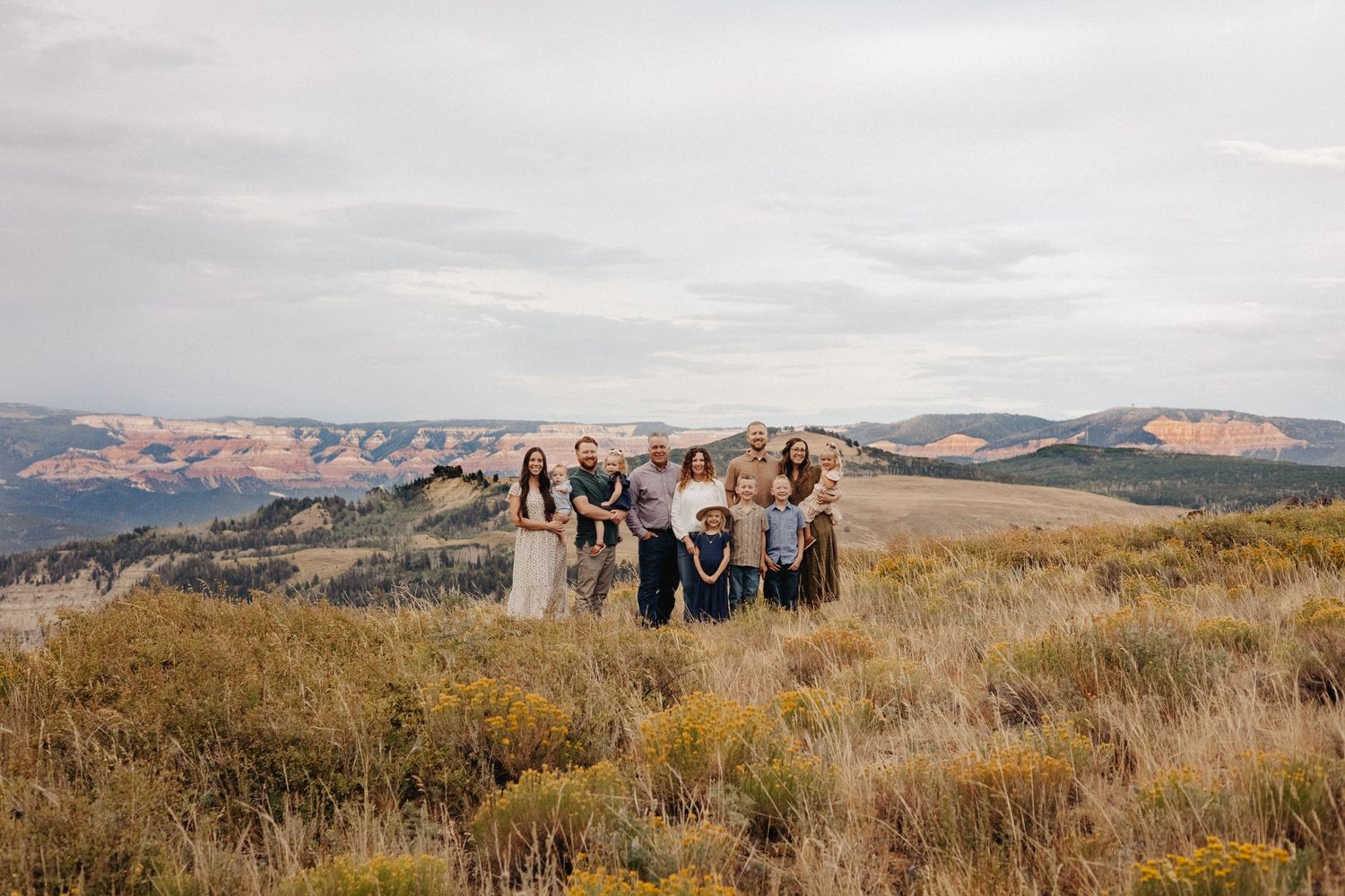 A group of people stand in a scenic mountain landscape with golden grass and rolling hills in the background.