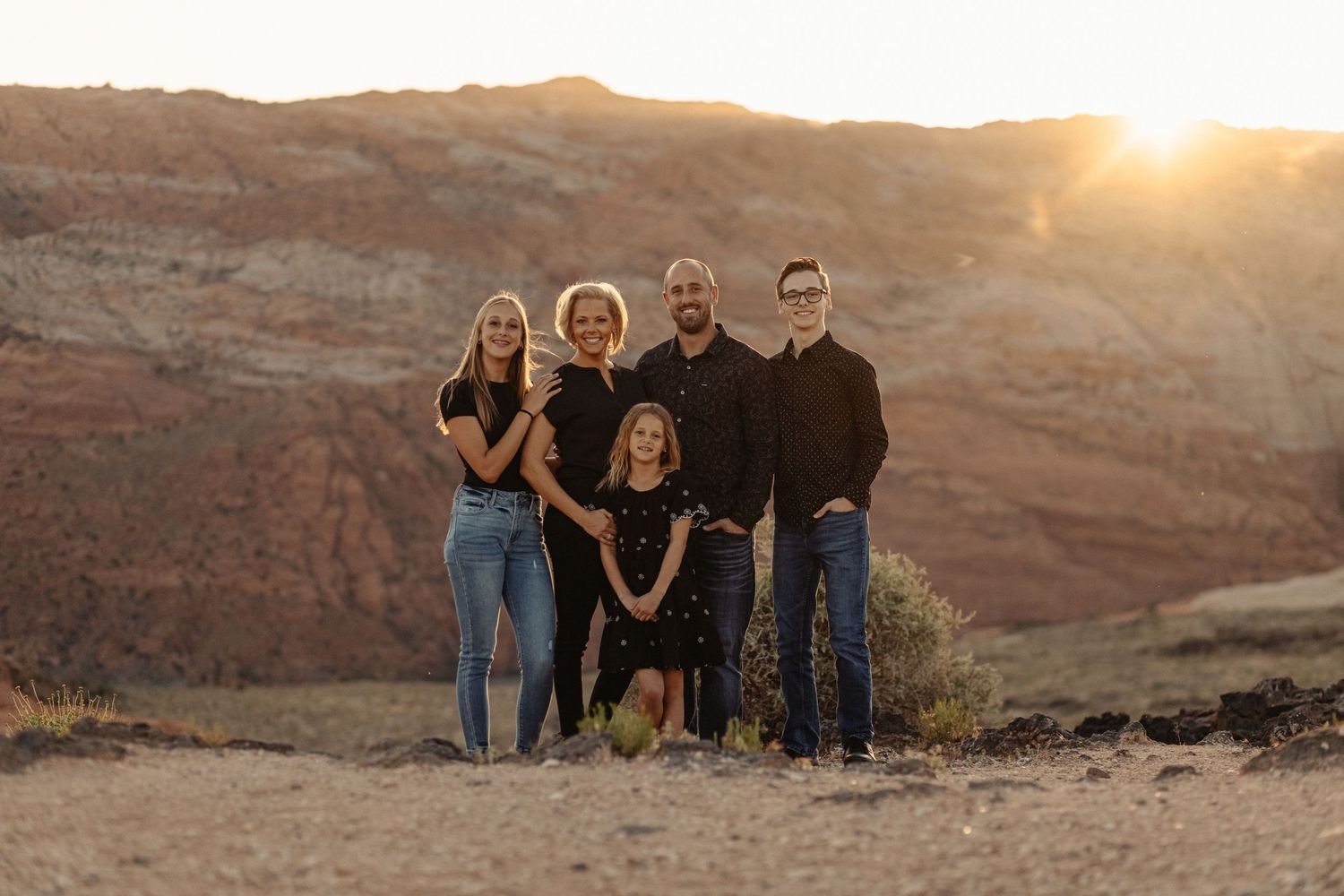 Family gathering for photos in desert landscape at golden hour.
