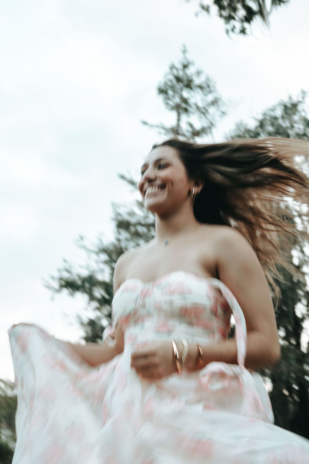 Motion-blur portrait capturing joyful spinning movement in floral dress outdoors.