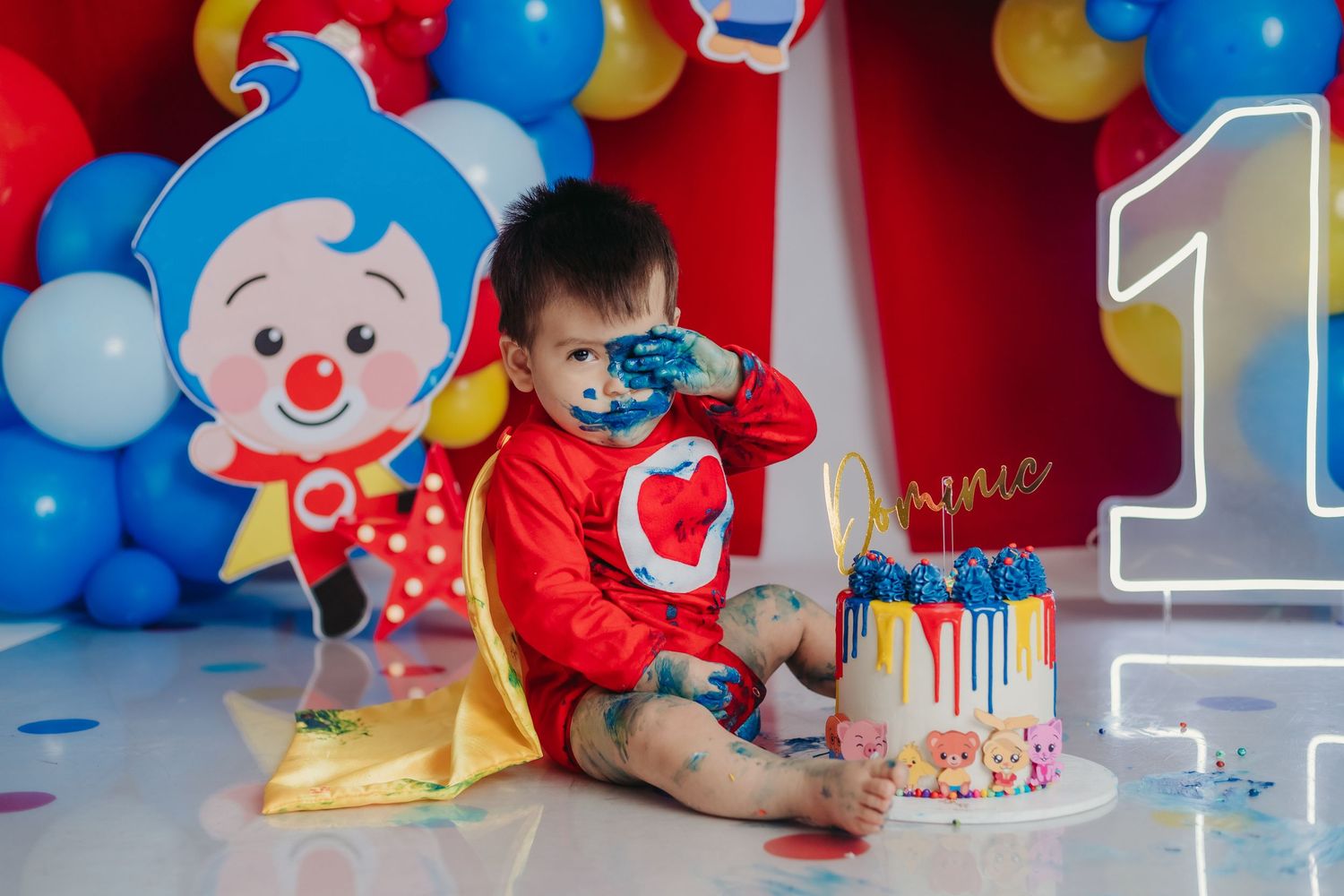 Birthday party scene with blue and red balloons, clown decorations, and a festive cake.