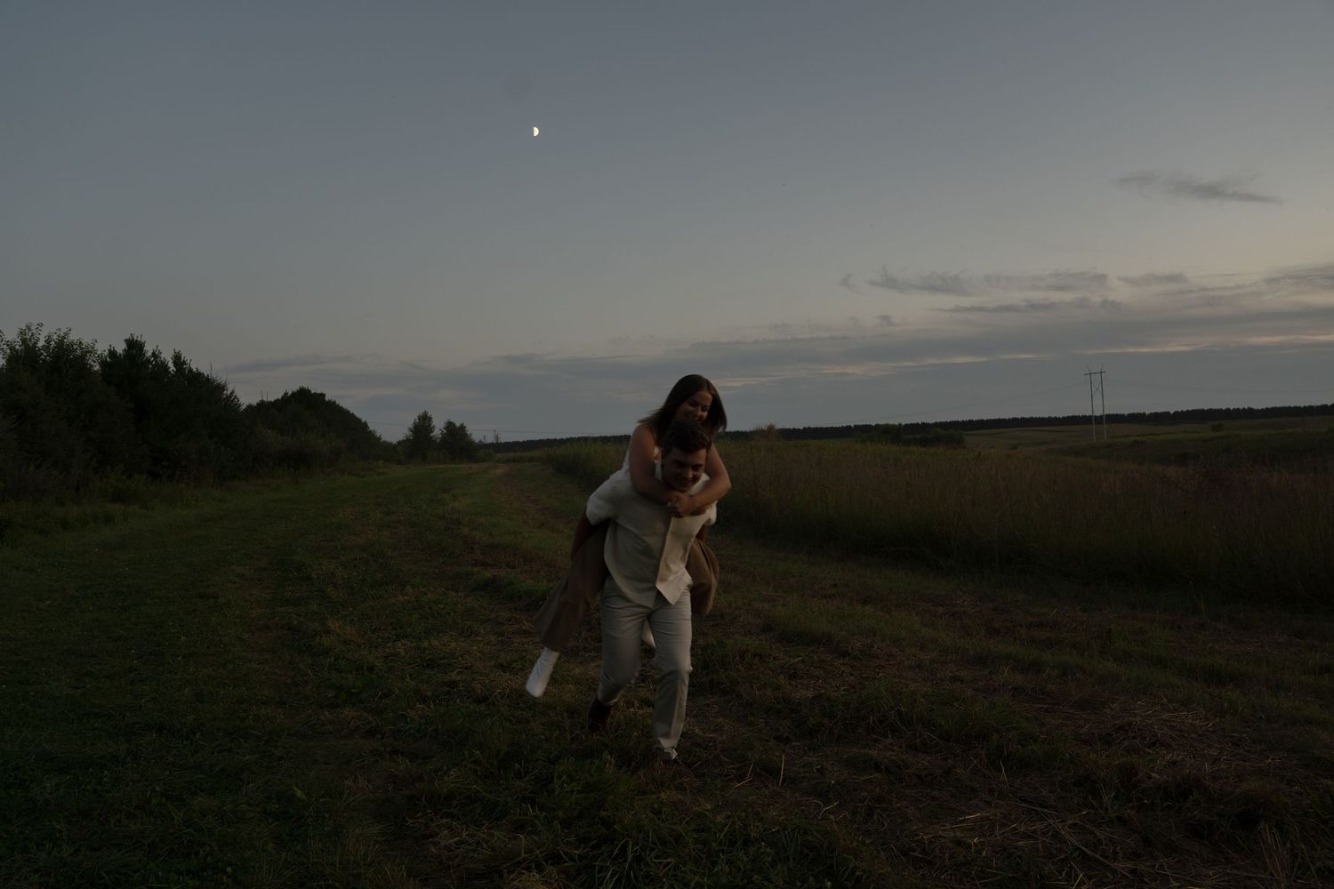 Couple embraces in silhouette against dusky sky during sunset wedding photography session.