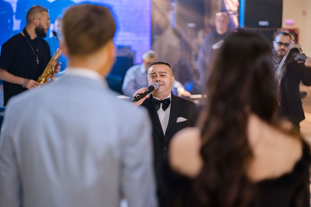 Musicians performing on stage with blue lighting at an indoor event.