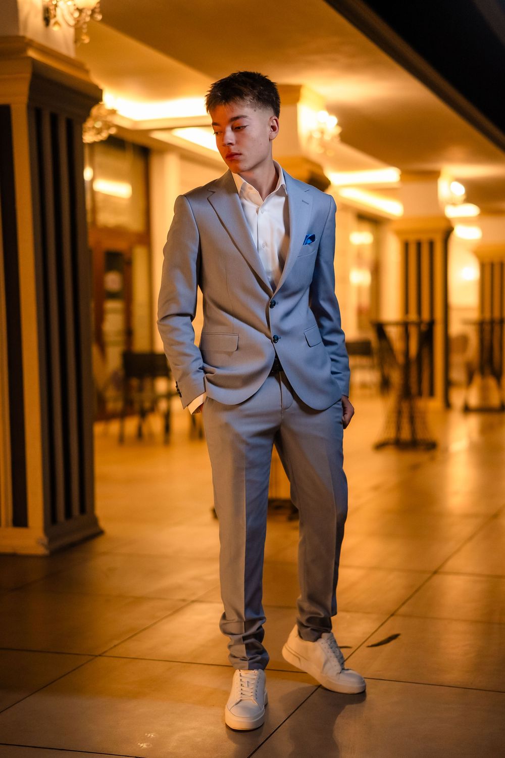Person in gray suit poses in an elegantly lit indoor venue.