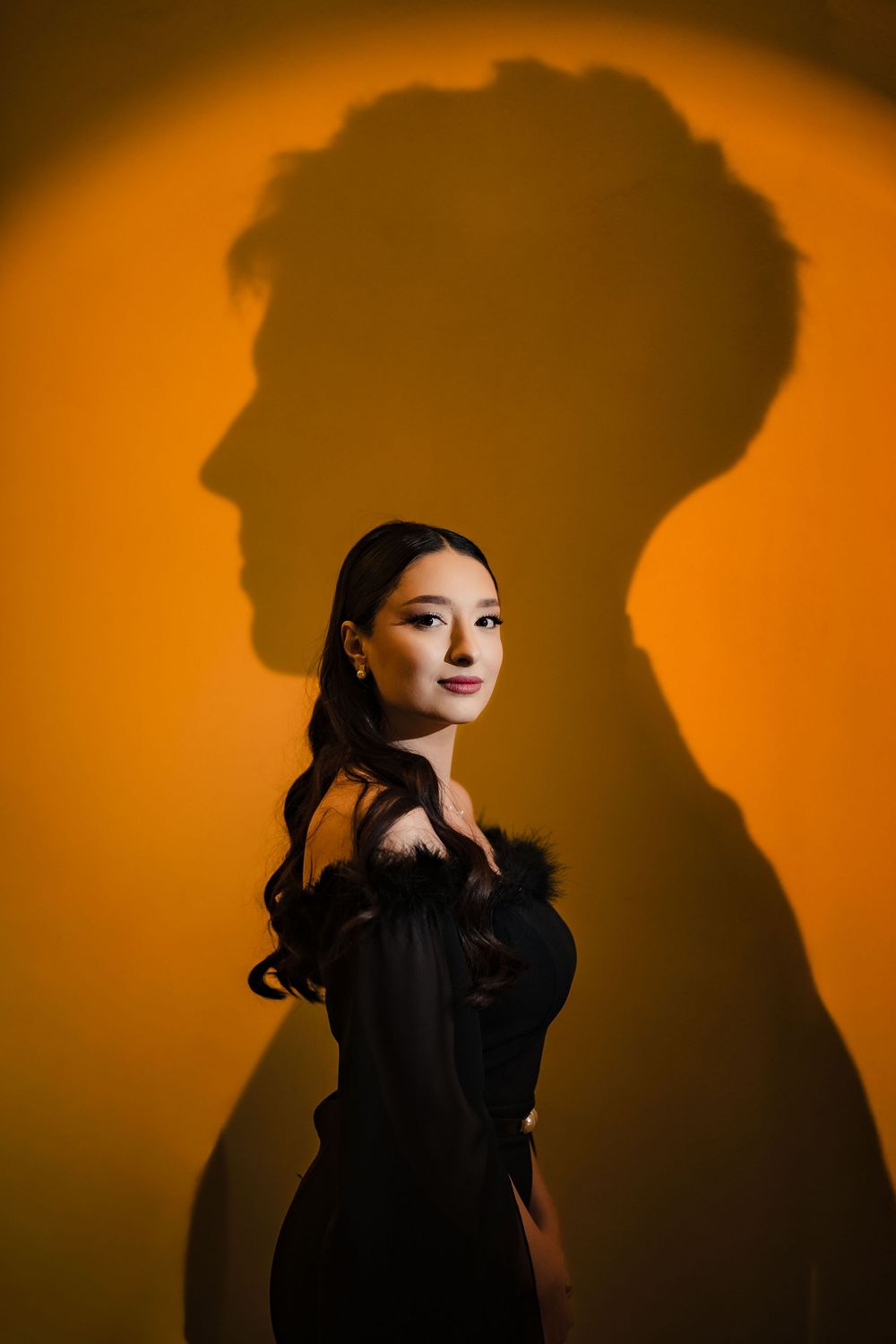 Artistic silhouette portraits against warm orange background with dramatic lighting.