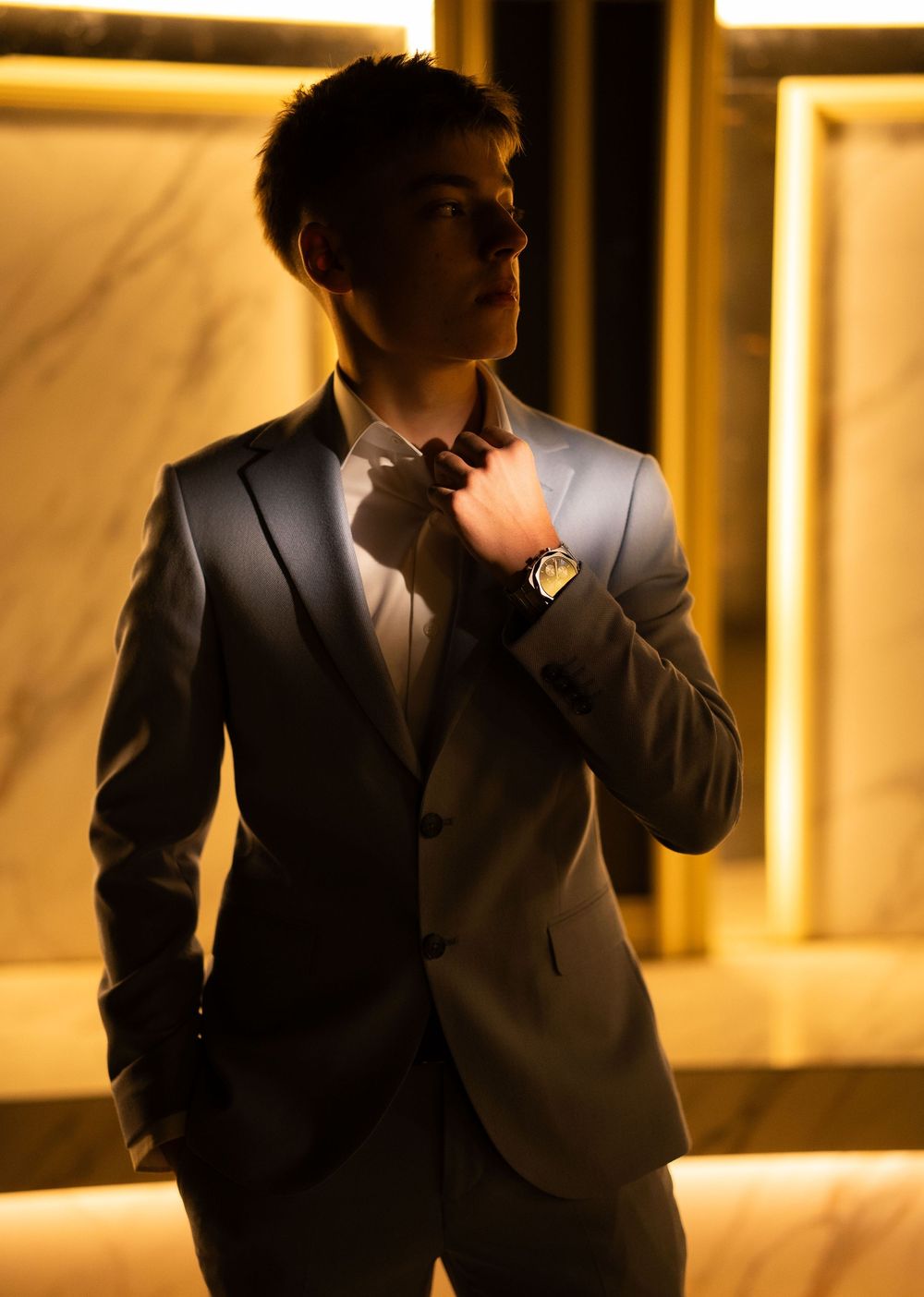 Moody fashion portraits in light blue suit with warm ambient lighting.
