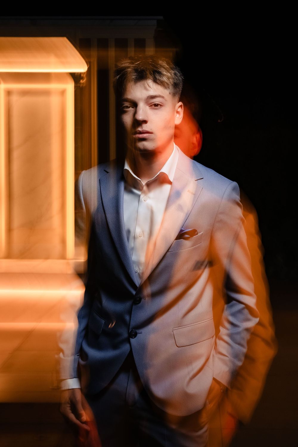 Fashion editorial shots in blue suit with dramatic low-key lighting.