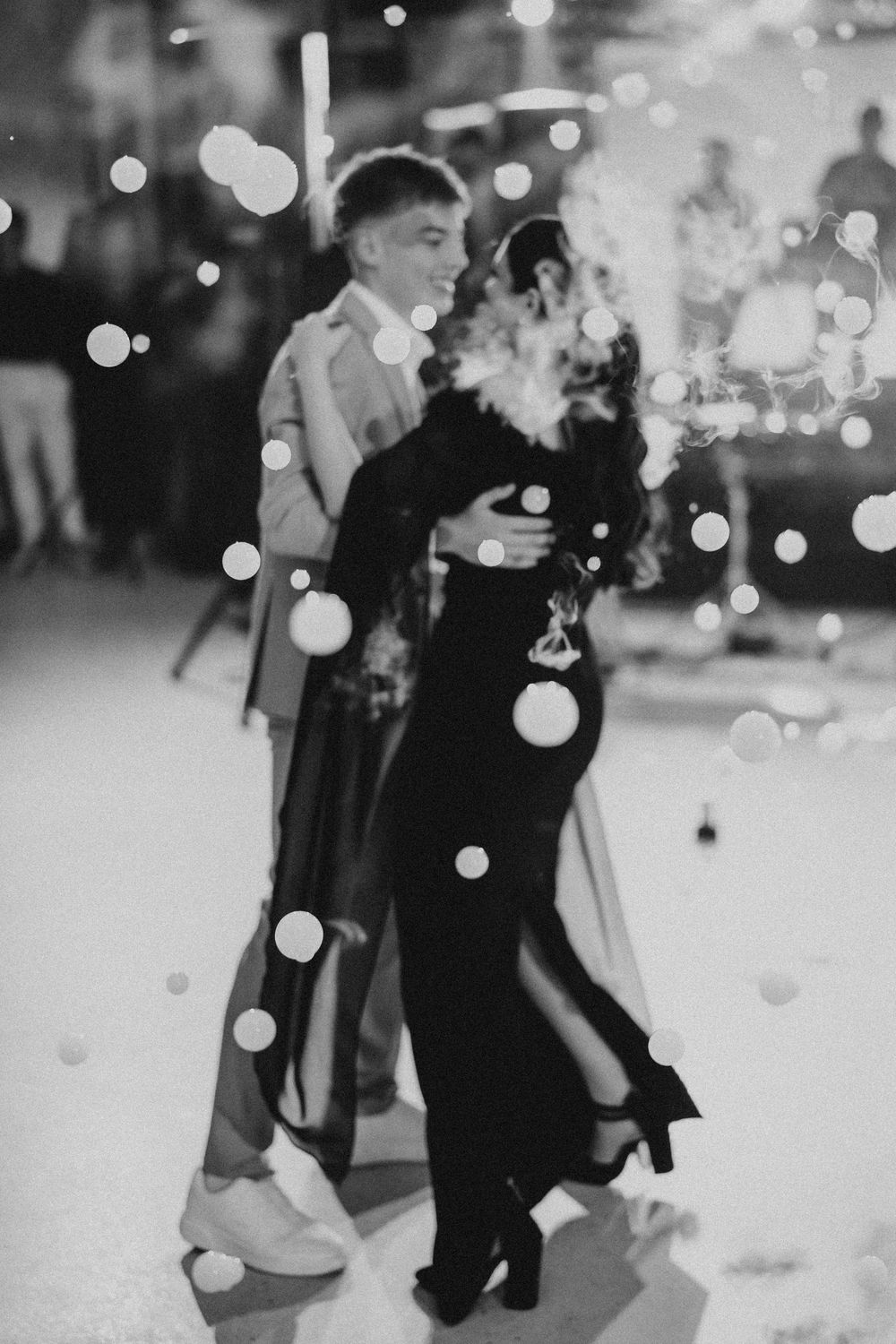 Black and white photo of people dancing at an event with bokeh light effects.