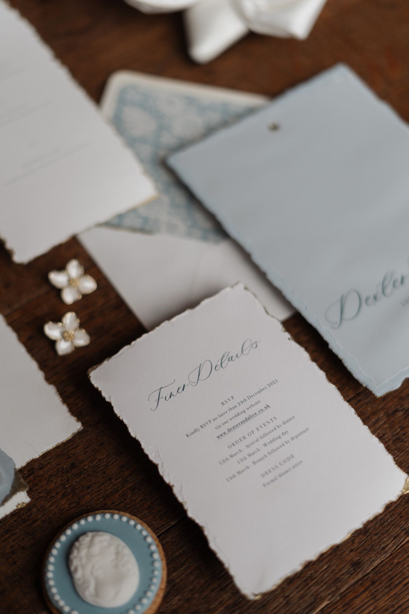 Wedding invitation details with delicate paper and floral elements on wooden surface.
