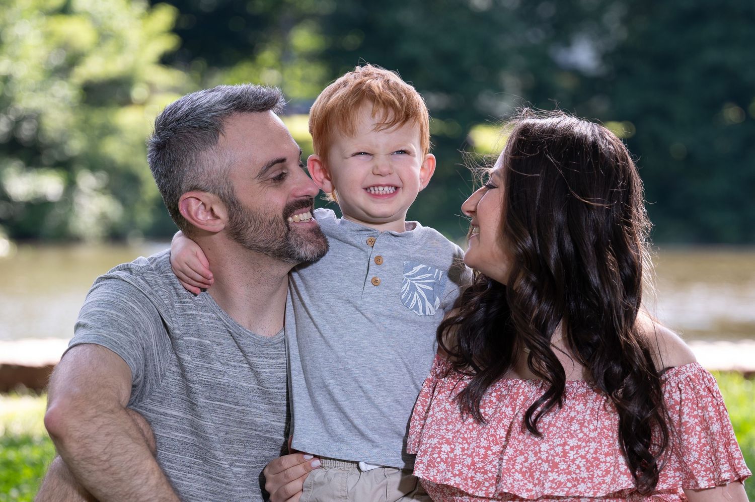 A heartwarming family moment captured outdoors near a lake or pond.