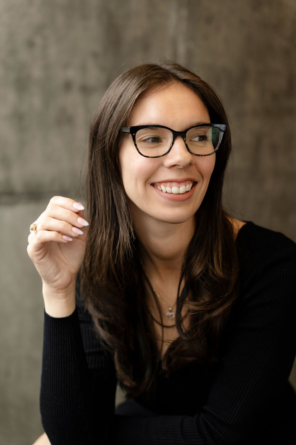 Portrait of a person with glasses and dark hair smiling warmly at the camera.