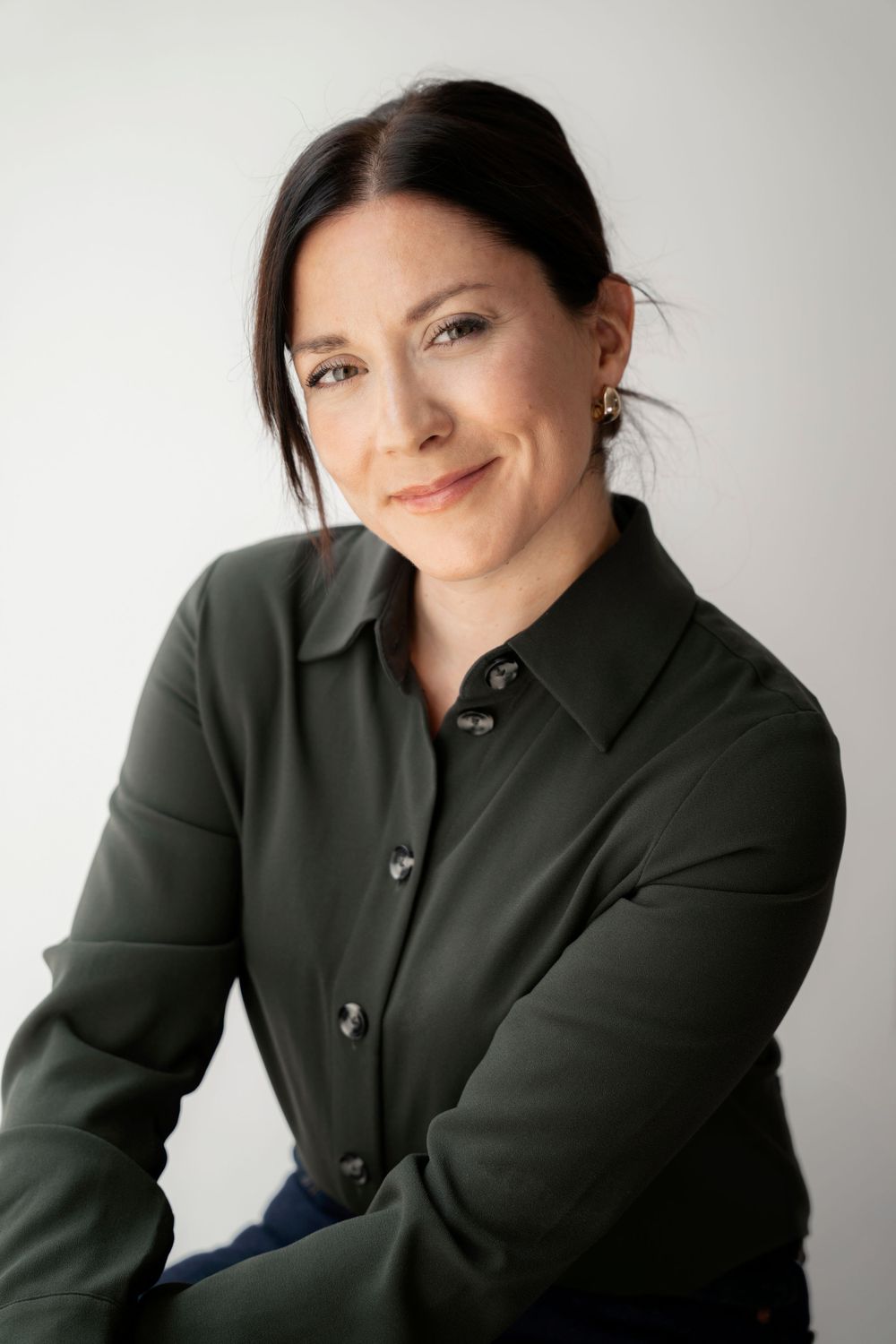 Professional headshot of a person wearing a dark button-up shirt against a light background.