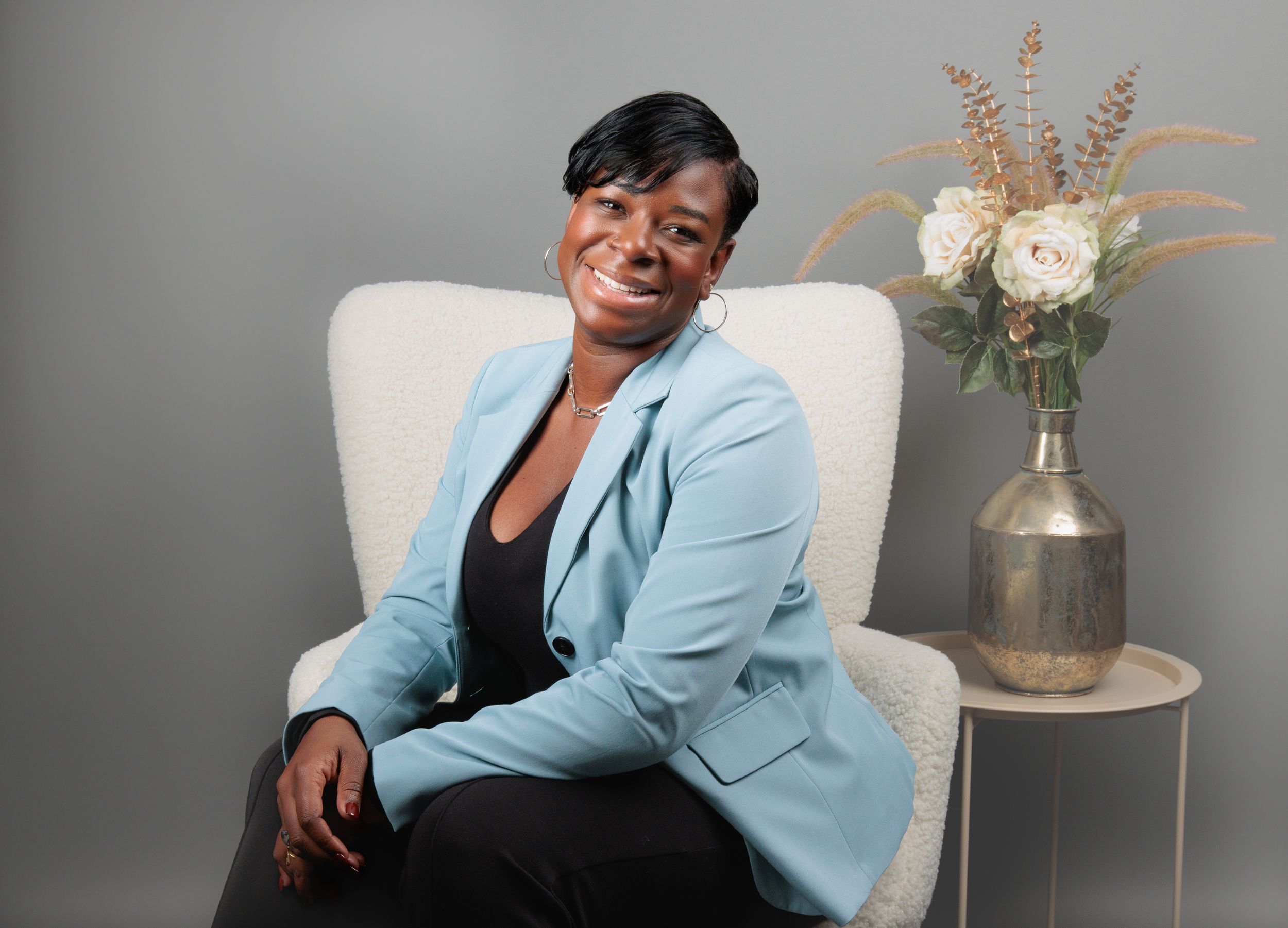 Professional portrait series showing person in light blue blazer posing against grey background with floral decor.