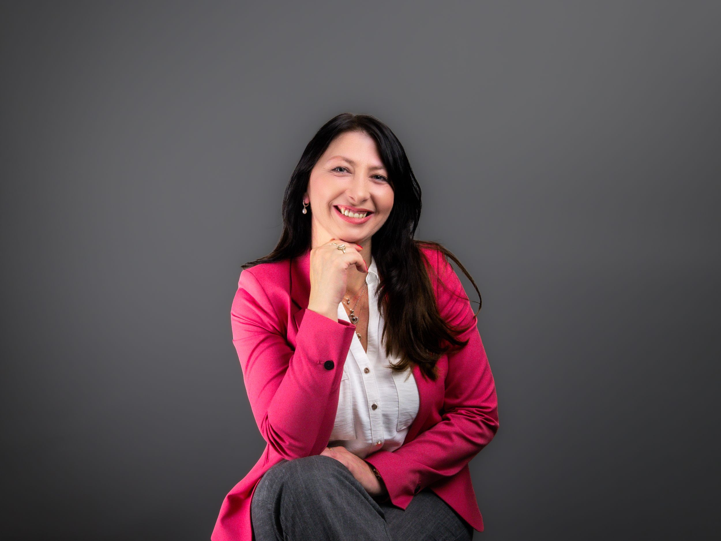 Professional portrait series showing a person in a bright pink blazer against a dark background posing expressively.