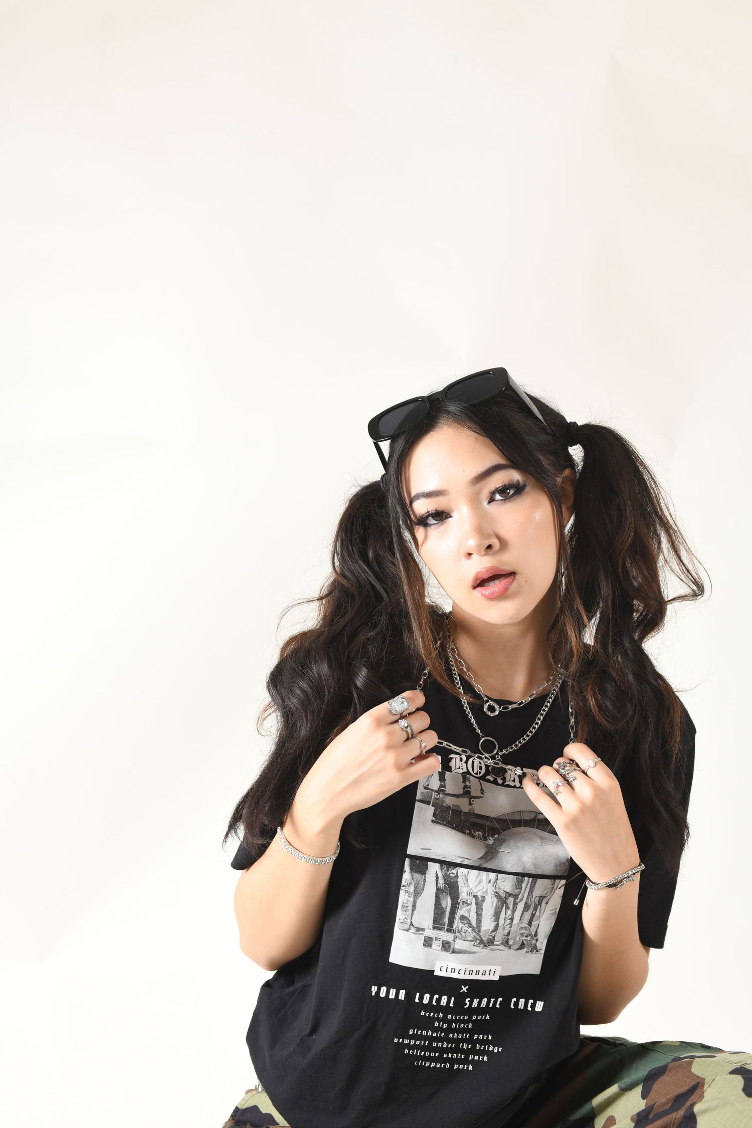 Portrait in black graphic t-shirt with hair ribbons against white background.