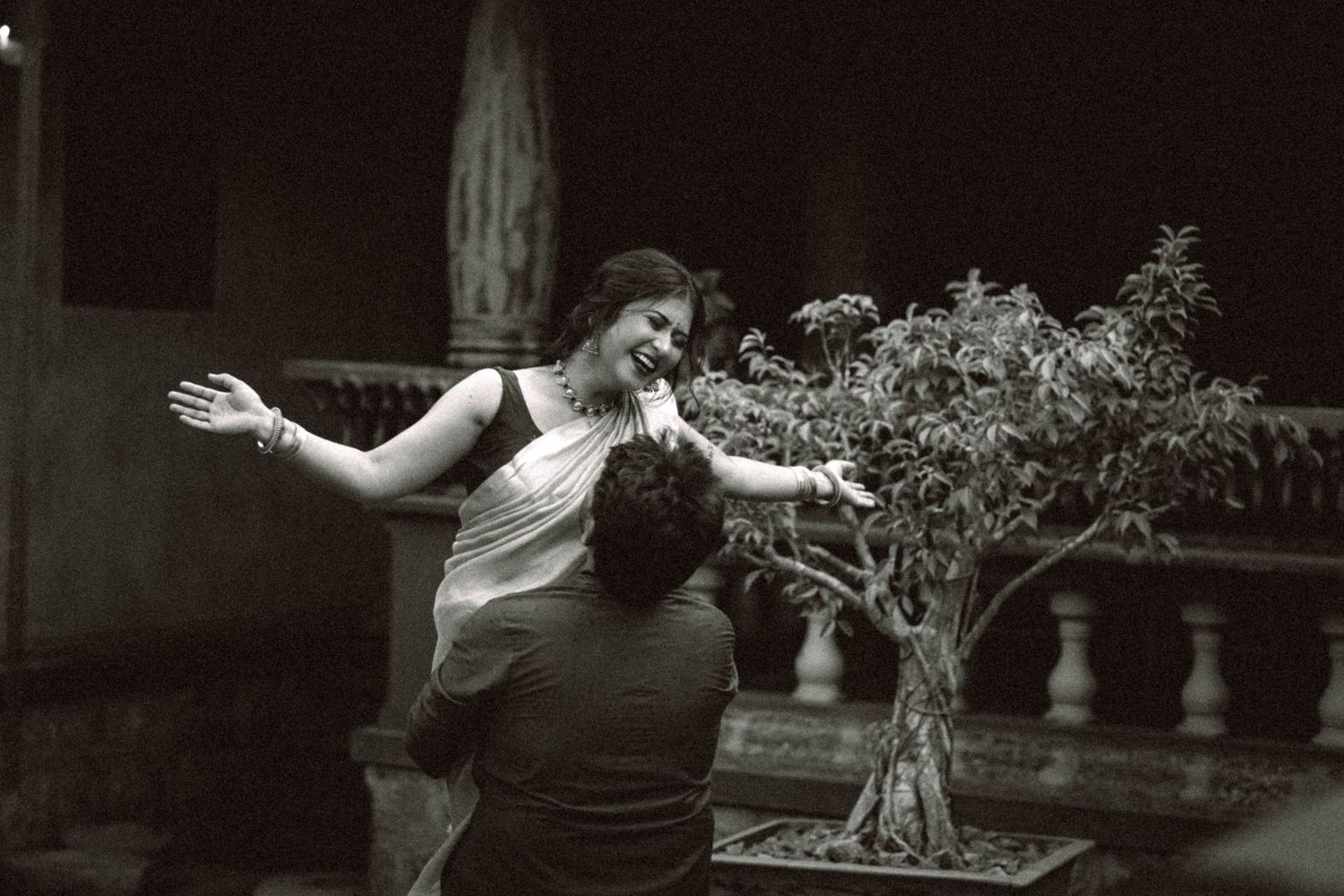 Romantic black and white dance scene in a garden with decorative plants.